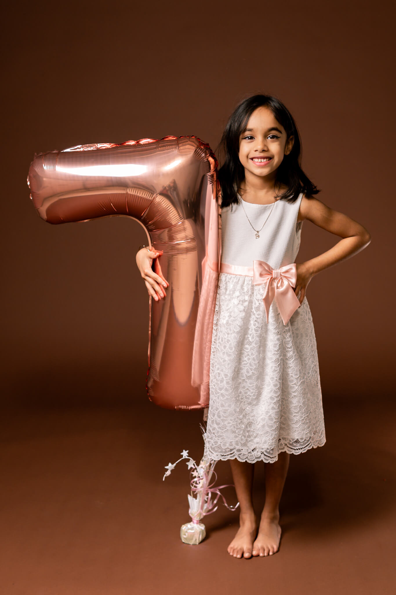 A 7-year-old girl in a sparkly dress posing for her birthday portrait in a professional studio