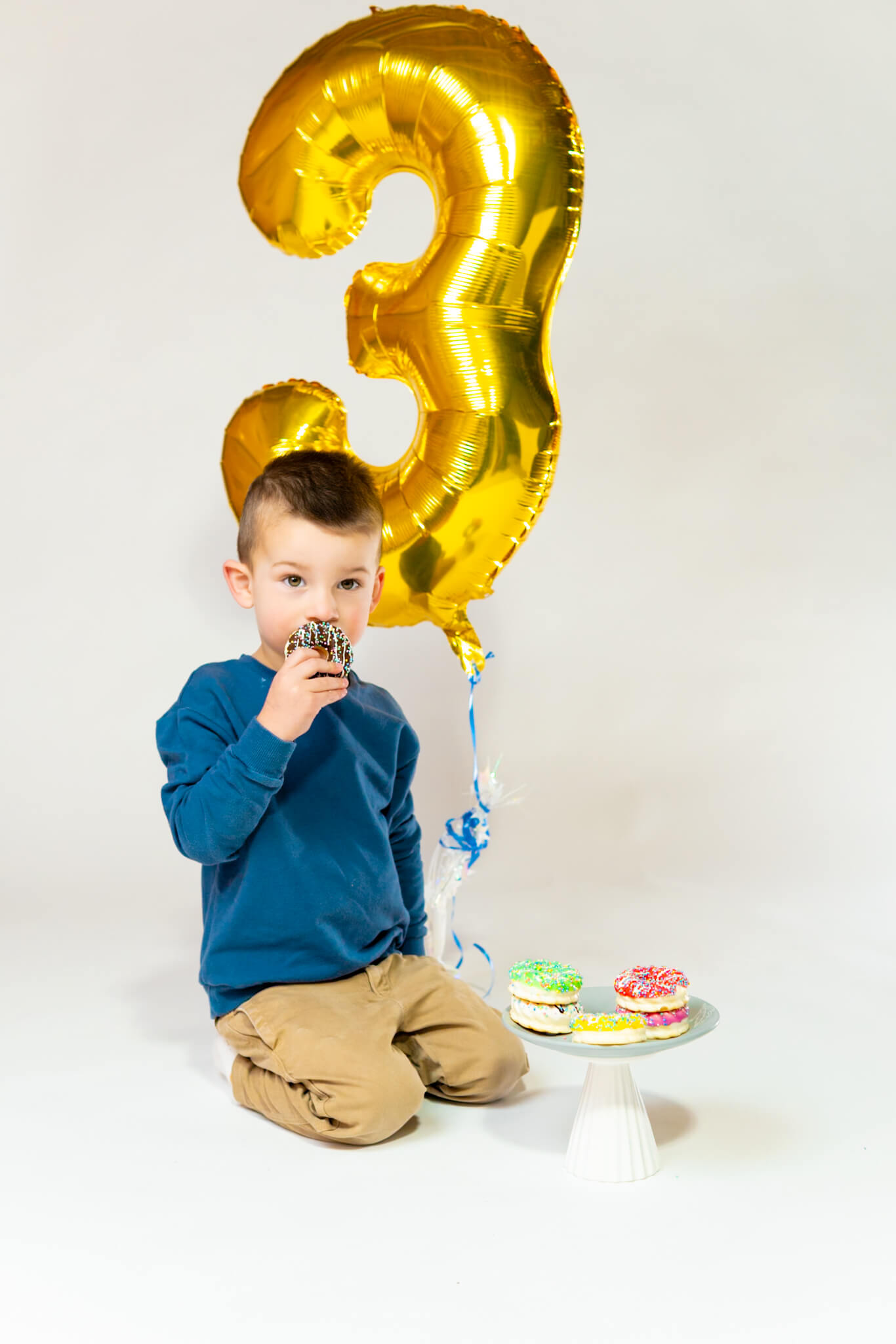 Toddler playing with balloons during a birthday session