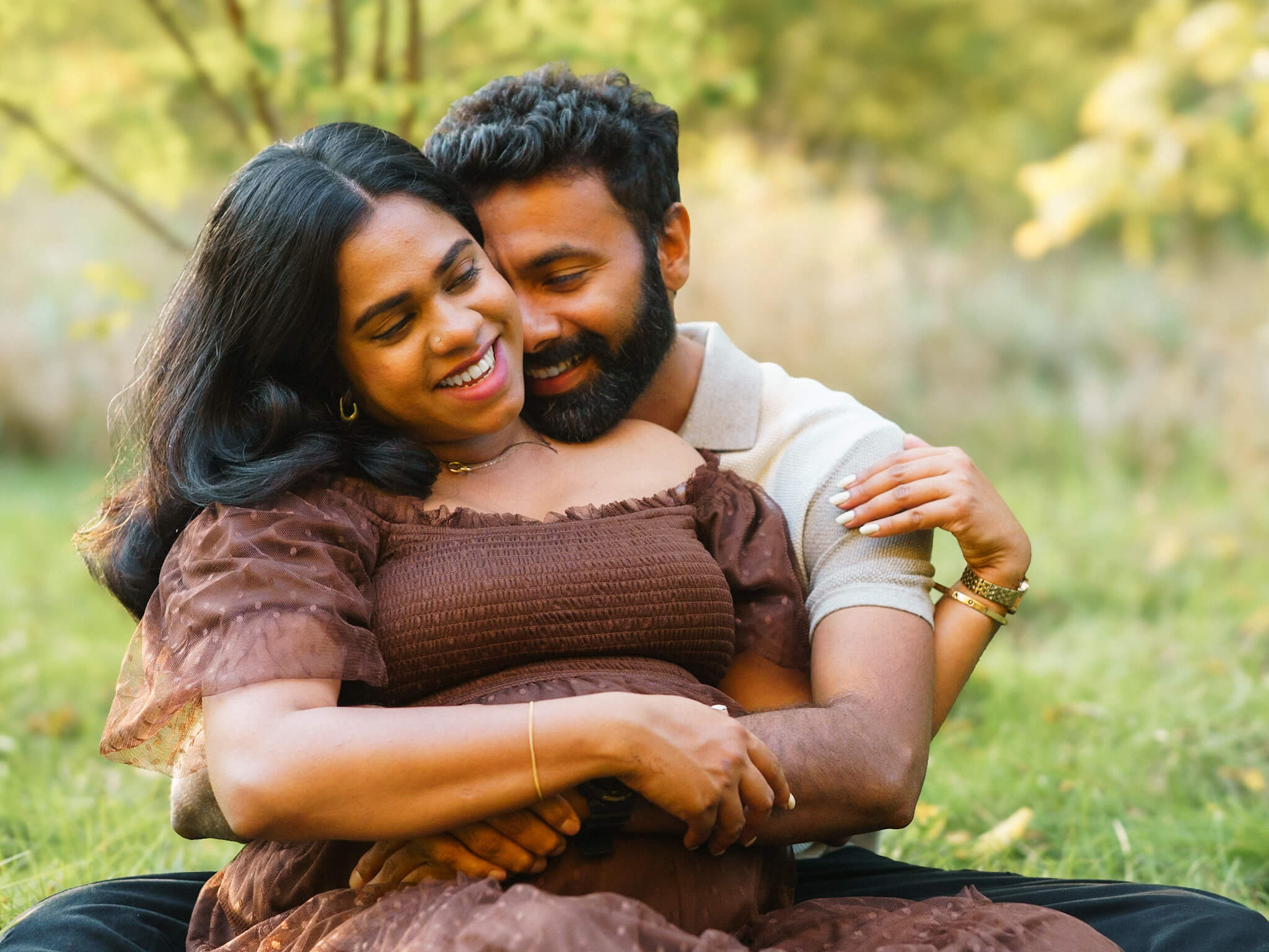 Expectant couple sitting in a forest setting