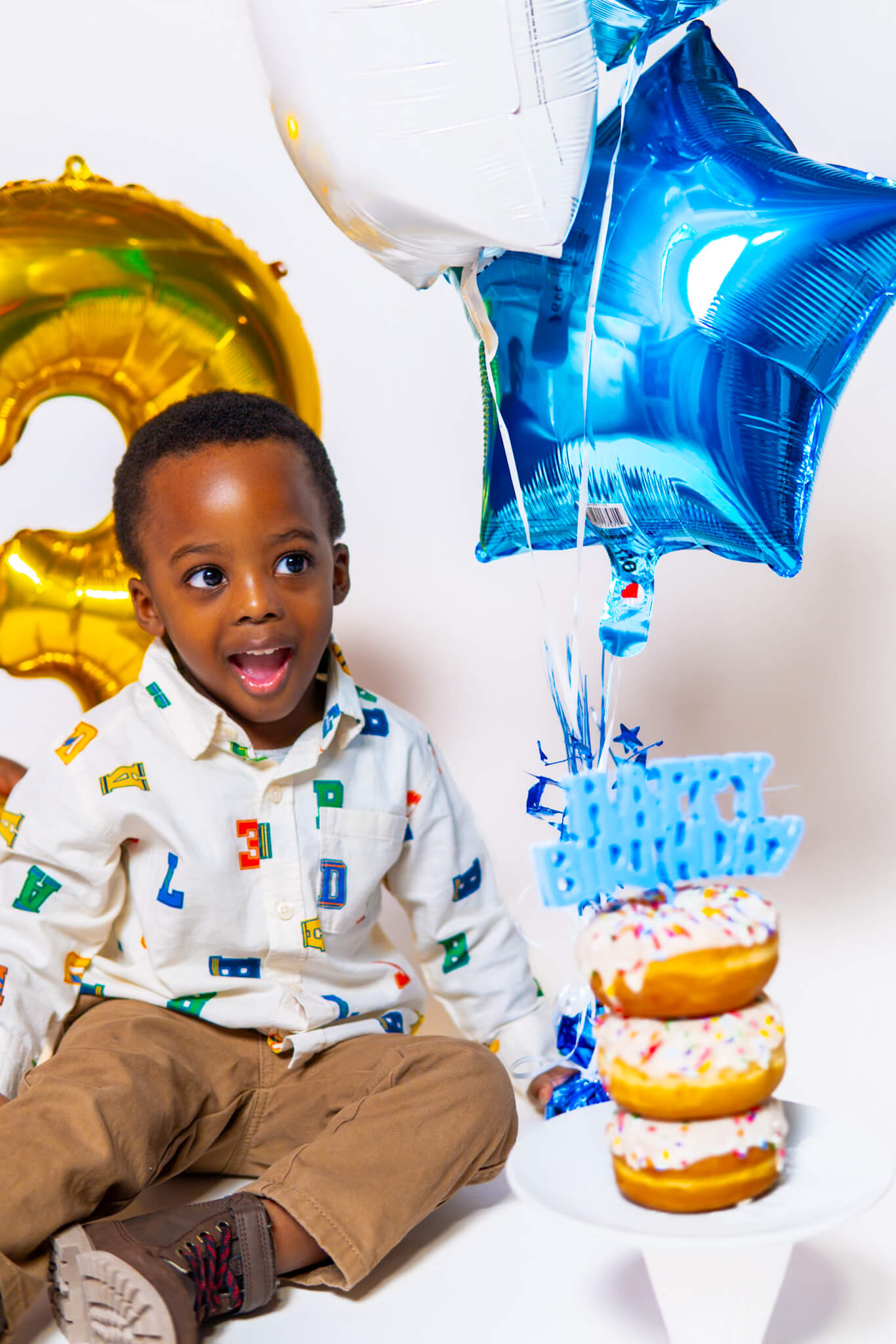 Close up of a joyful 3 year old boy sitting on the floor smiling