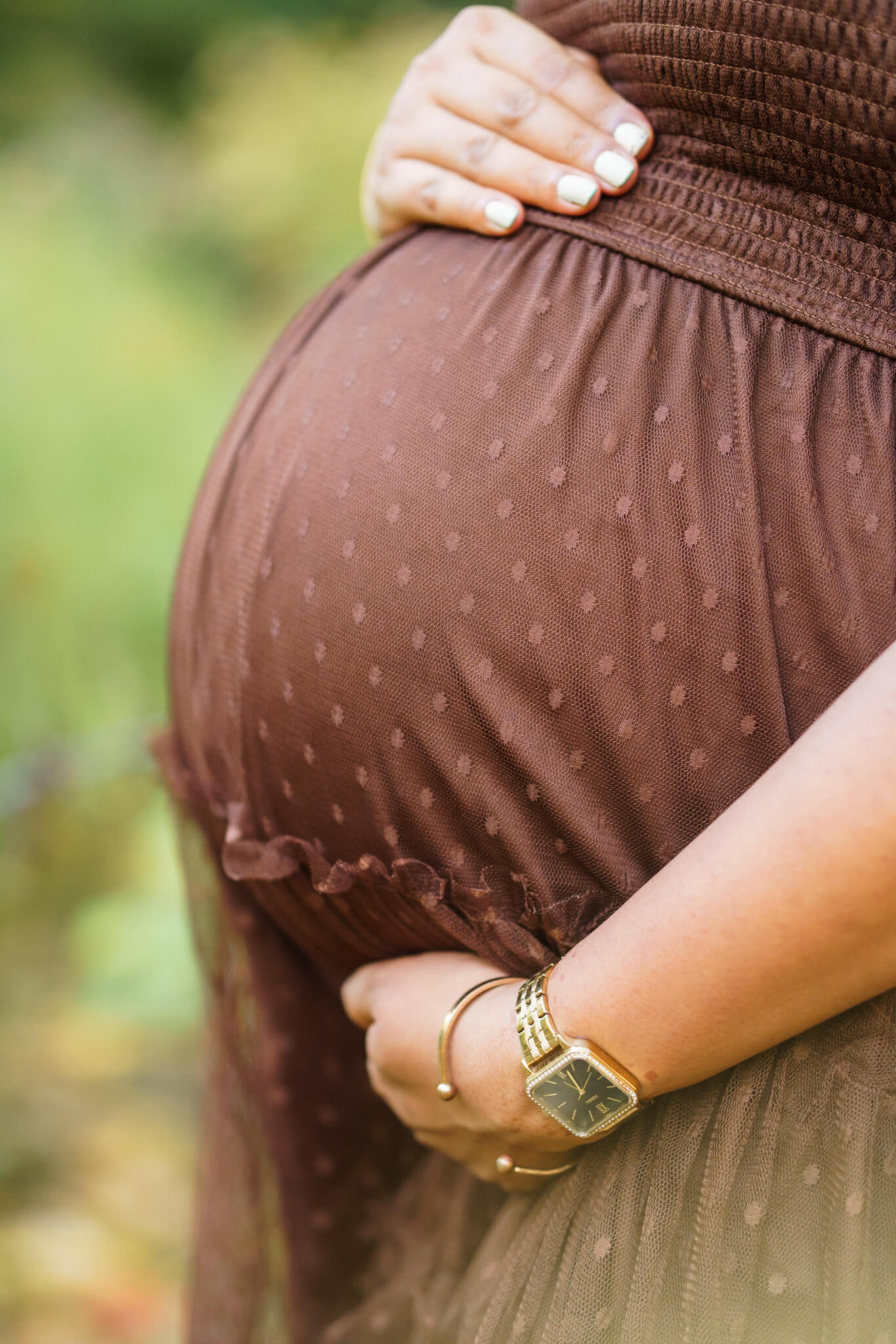 Close-up of a pregnant woman's belly in a brown dress