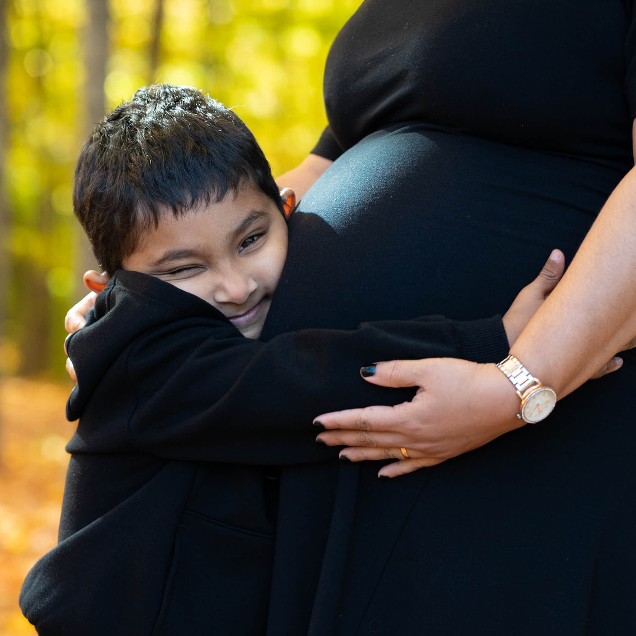 Boy hugging mother's pregnant belly in Cambridge