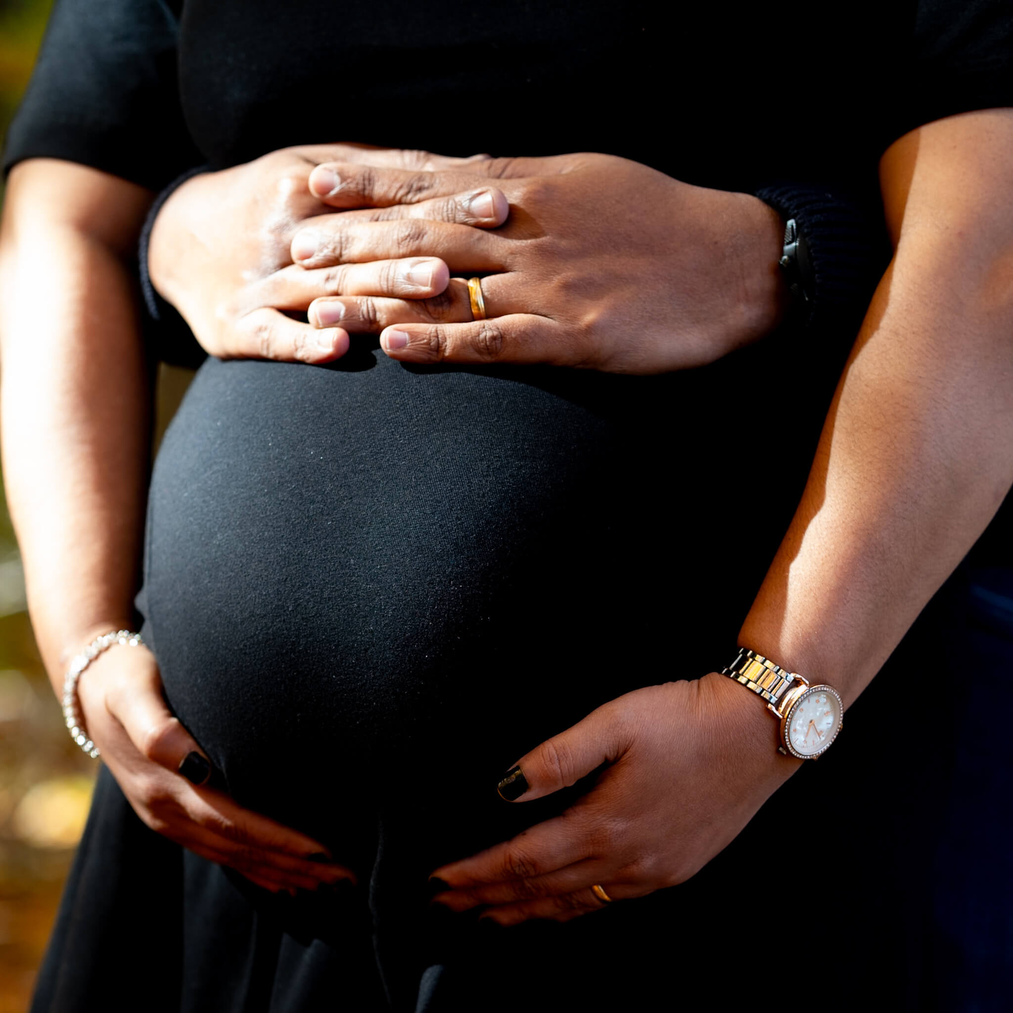 Parents' hands forming a heart shape on a baby bump