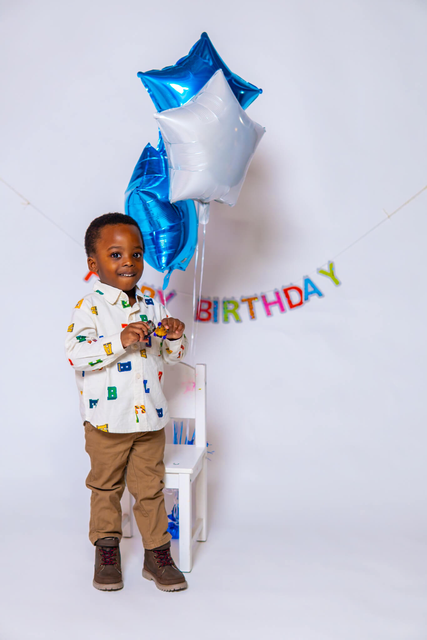 Birthday boy in patterned shirt with blue and silver balloons